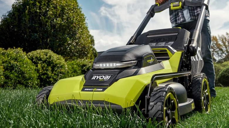A landscaper cutting a lawn with Ryobi mower