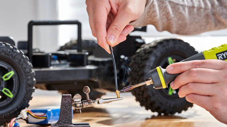 Person using Ryobi soldering pen to solder components of an RC car