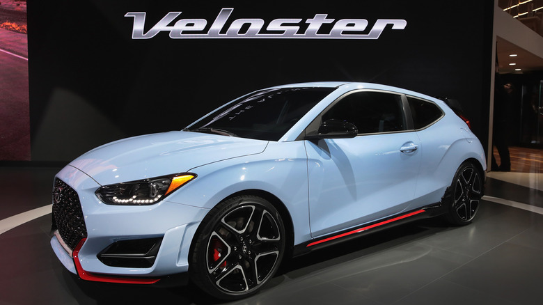 A blue Hyundai Veloster N parked inside an industrial facility with little in the background./