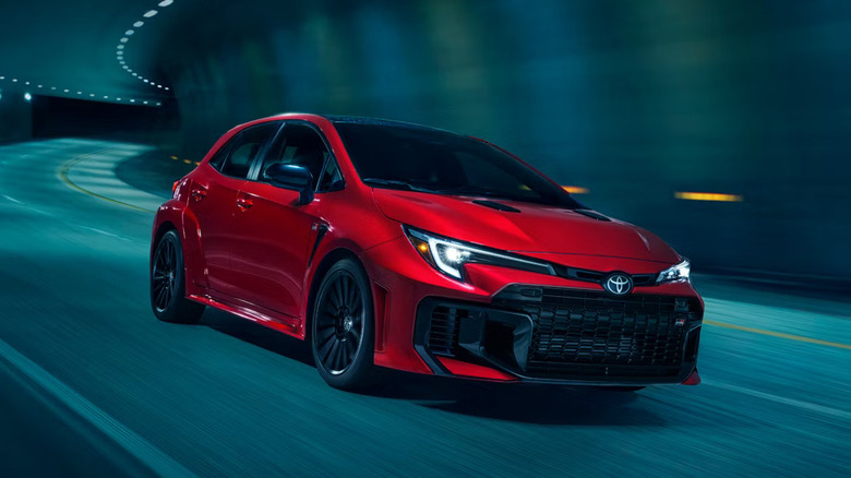 A red GR Corolla from the 2026 model year taking a gentle curve in an underground tunnel road.