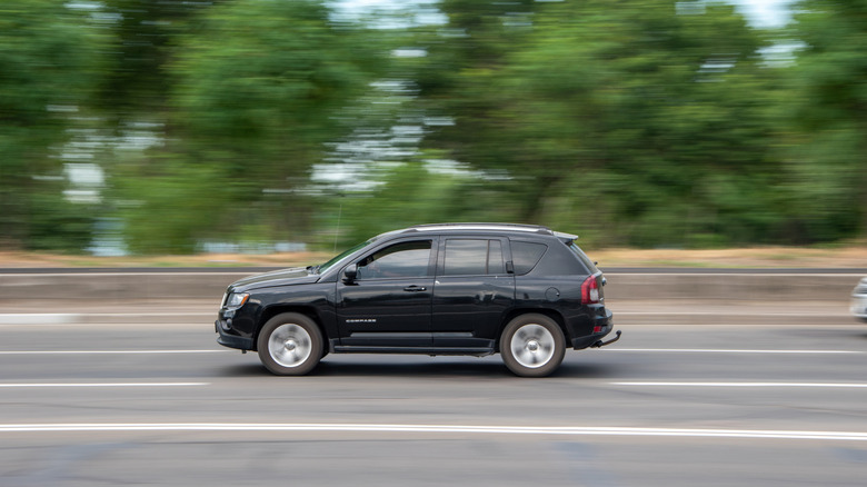 A black Jeep Compass for the 2021 model year moving right to left down a road in Kyiv, Ukraine.