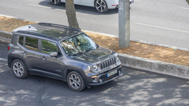 A gray Jeep Renegade photographed traveling down a road with moving traffic on it.