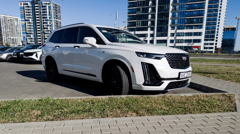 A front-right view of a 2025 Cadillac XT6, finished in white, parked at an angle in an outside lot.