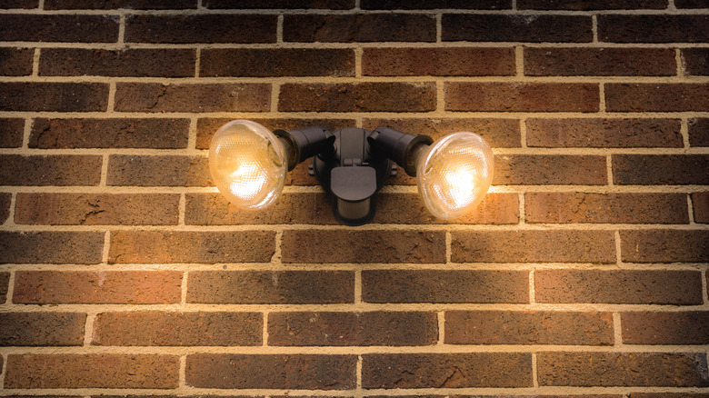 Two floodlights mounted to a brick wall