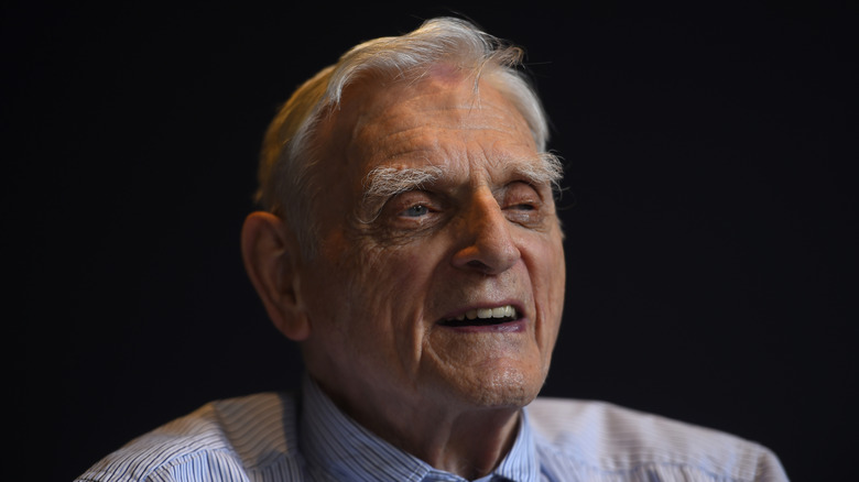 John B. Goodenough in front of a black background