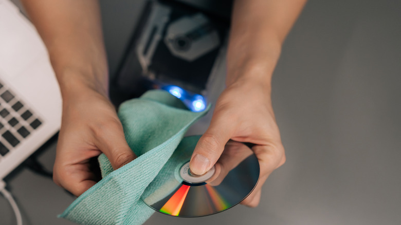 A person cleaning a disc with a microfiber cloth
