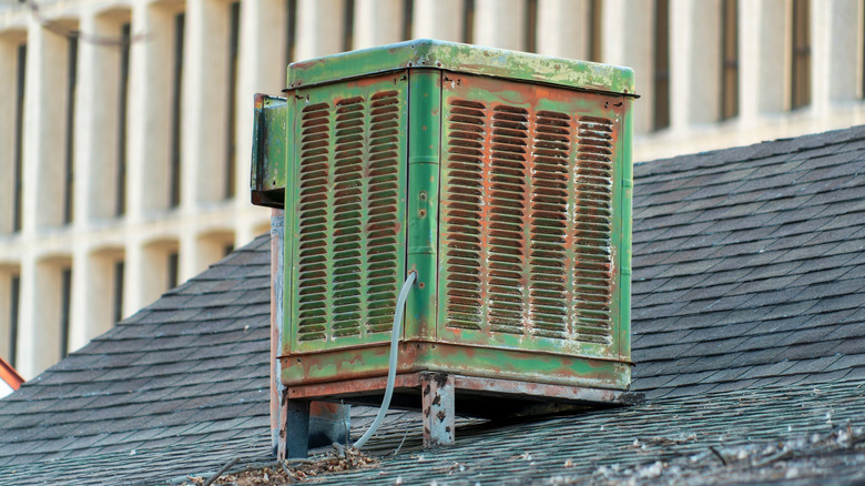 Weathered-looking green and rusted swamp cooler unit on top of a roof