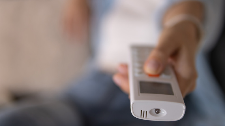 Hand holding air conditioner remote pointing toward camera