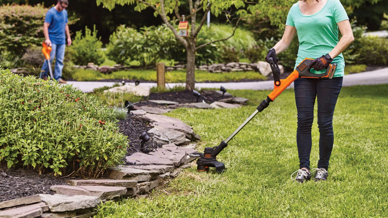 A person using the Black & Decker Straight Shaft Cordless String Trimmer/Edger on a lawn