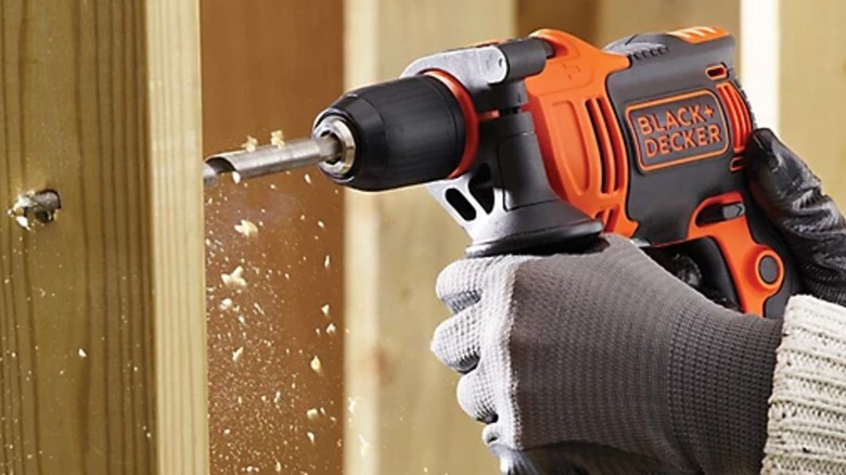 Close up of a worker drilling through stud with Black+Decker hammer drill