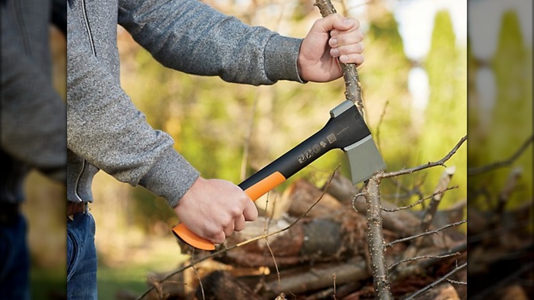 Worker cutting branches with Fiskars hatchet in an outdoor setting