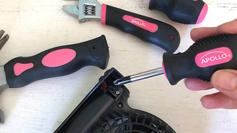 Assortment of Apollo stubby tools with a screwdriver in a person's hand unscrewing a screw from a fan