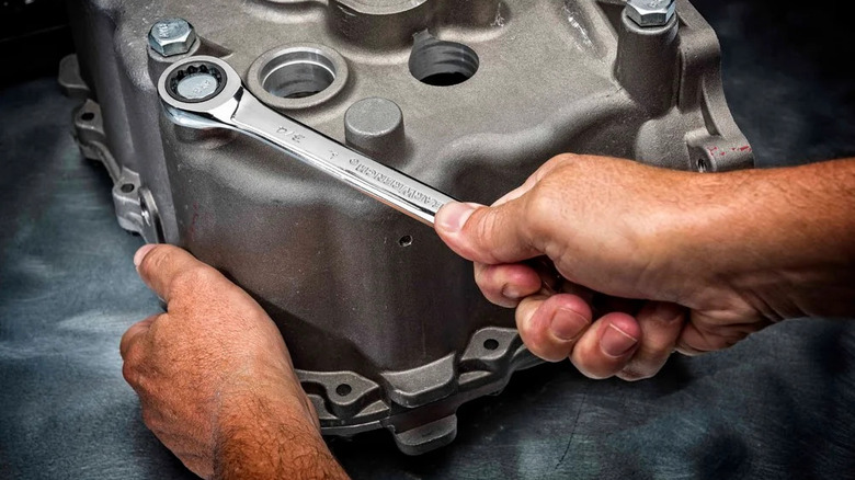One hand holding a GearWrench ratchet wrench working on a vehicle part