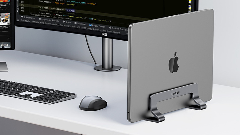 A vertical stand holding a Macbook on a desk