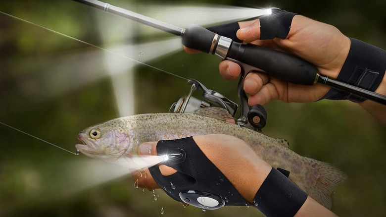 Image showing two hands, both wearing flashlight gloves, one hand holding a fish and one hand holding a fishing rod
