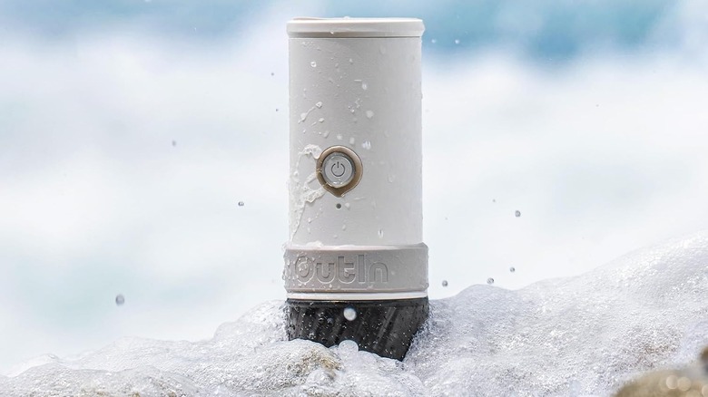 OutIn battery-powered espresso machine sitting in foamy water