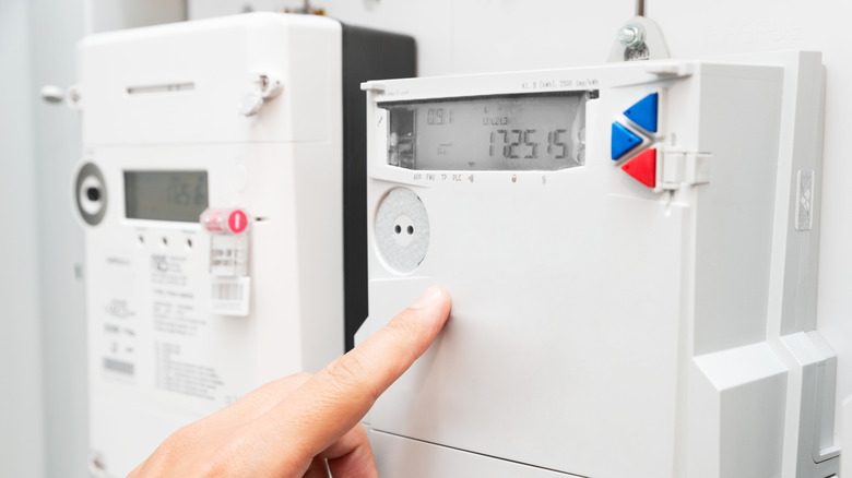 A person pointing to the electrical panel outside a house
