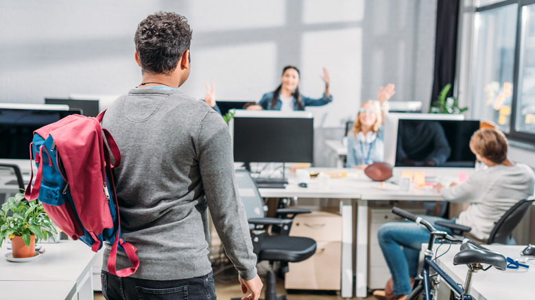 A man wearing a backpack walking into an office