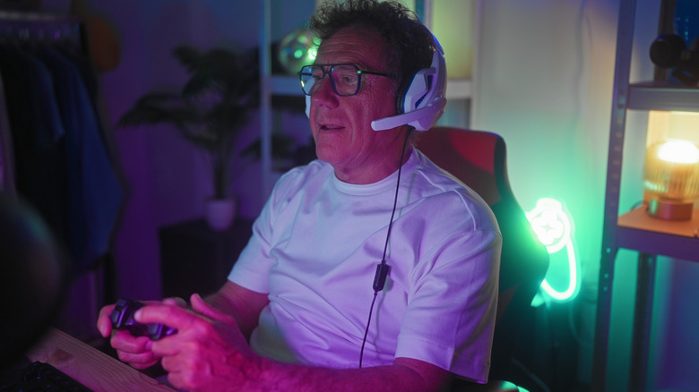 A man gaming at a desk with a controller and headphones