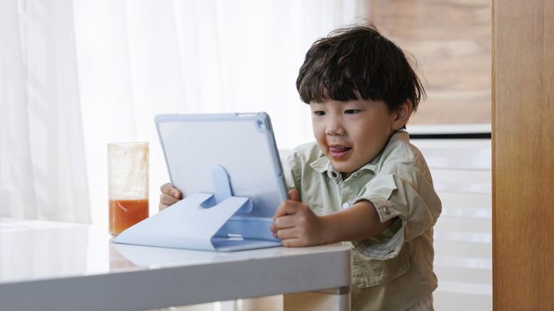 Child sitting at a table with a tablet