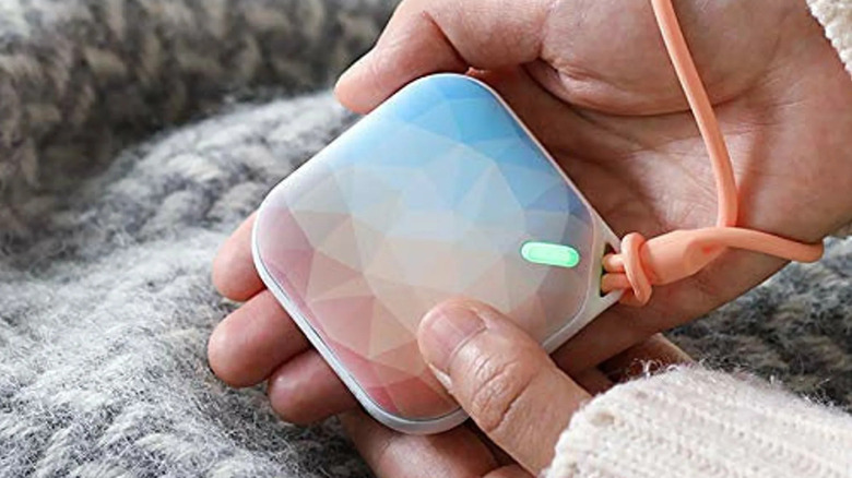 The Orastone Rechargeable Hand Warmer in a person's palm