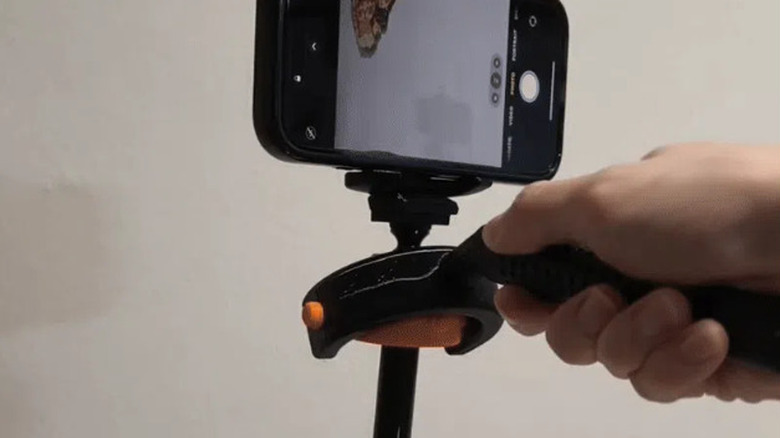 A person adjusting a phone attached to a gimbal stabilizer