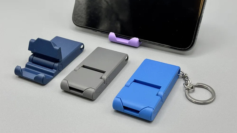 Three keychain phone stands in front of a phone