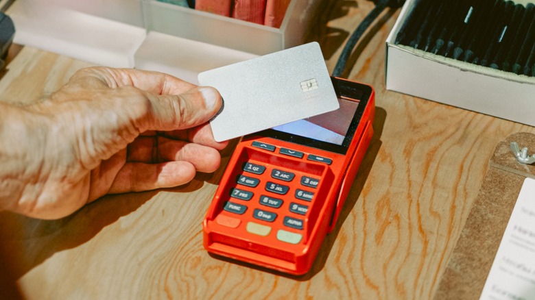 Hand making a credit card purchase on an orange card reader