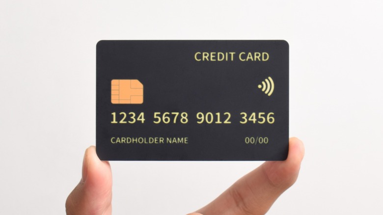 Fingers holding a generic black credit card