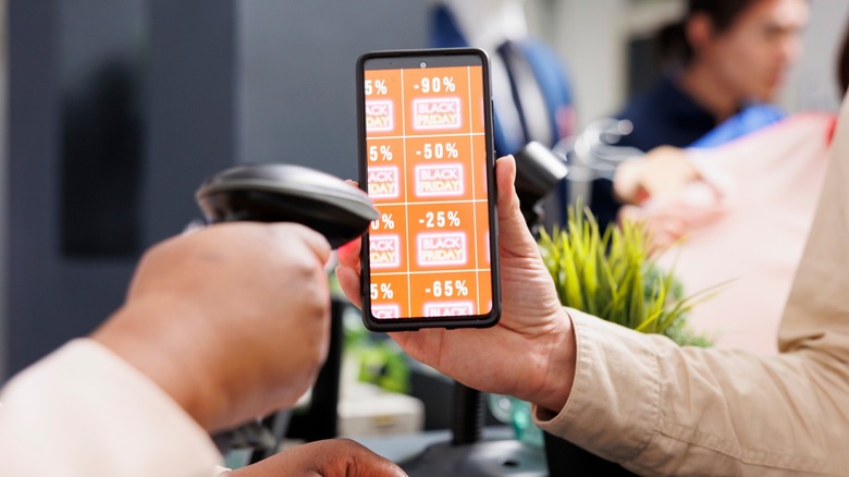 Close-up of a cashier scanning a coupon on a smartphone