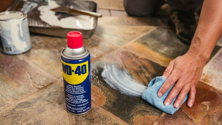Person wiping the paint off the floor with a can of WD-40 in the front