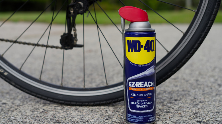 A bottle of WD-40 in front of a bicycle wheel