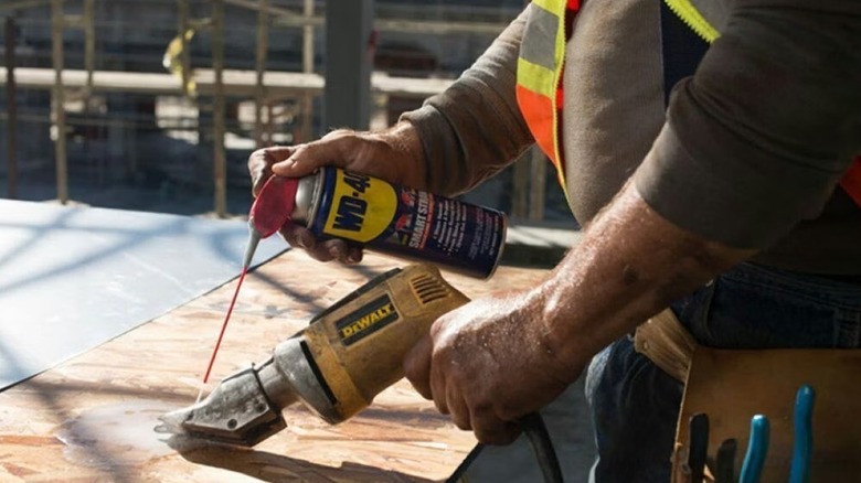 Person spraying WD-40 on a power tool
