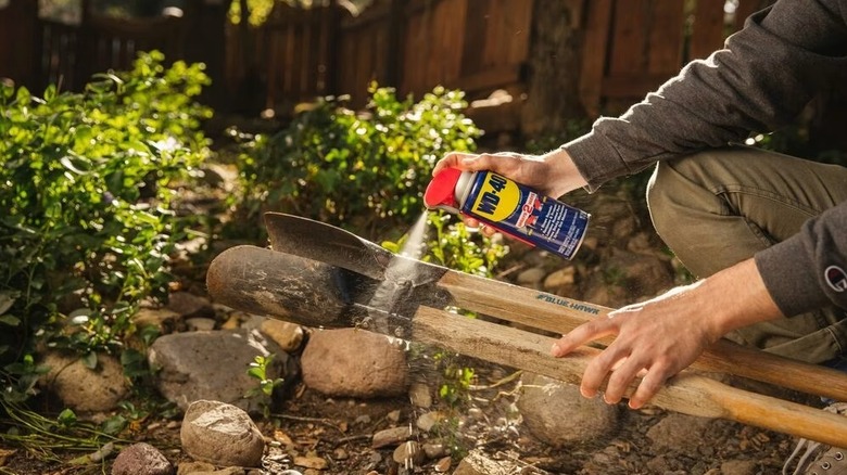 Person spraying WD-40 on rusty tools