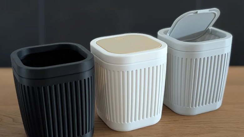 Three 3D-printed desktop trash bins sitting on a wooden surface