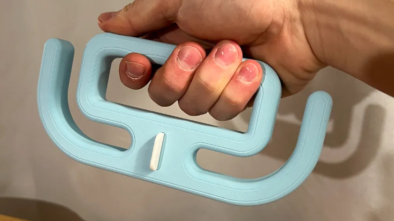 A hand holding a blue printed grocery bag holder