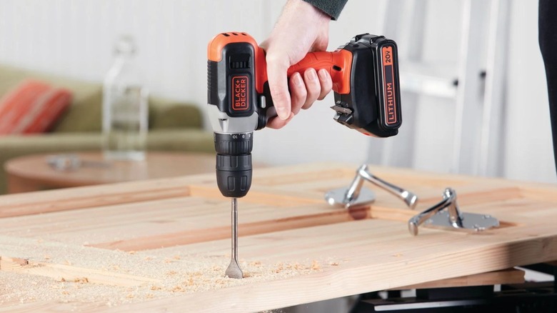 person using Black + Decker 20V Drill to bore hole
