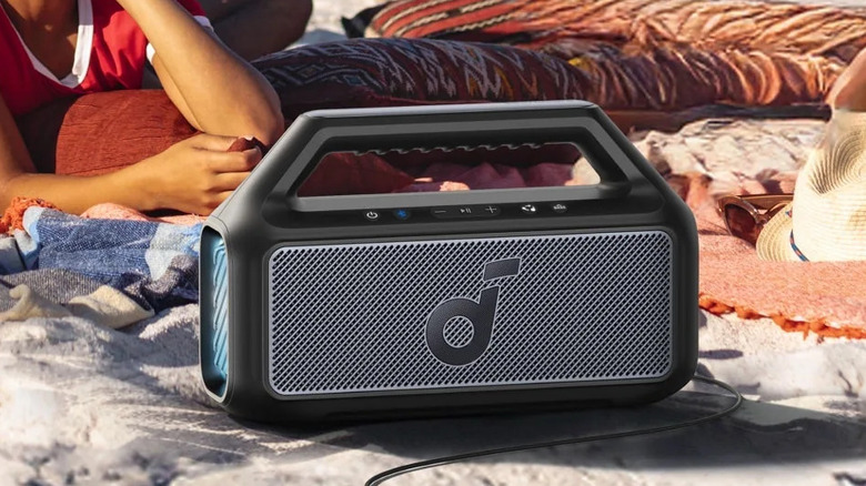 The Anker Soundcore Boom 2 speaker on the beach, with a person behind it