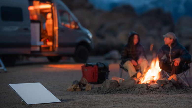 Starlink Roam set up near a couple by a campfire with RV in background