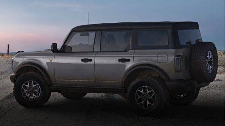 A gray Ford Bronco parked on dirt during late evening