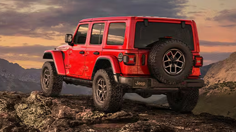 A red Jeep Wrangler parked on a rocky cliff