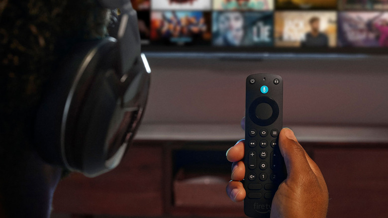 A person with headphones looking at their Fire TV Remote.