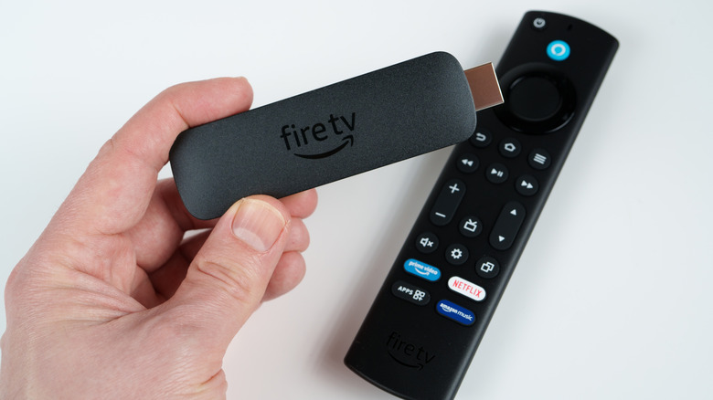 A Fire TV remote and stick held in fingers