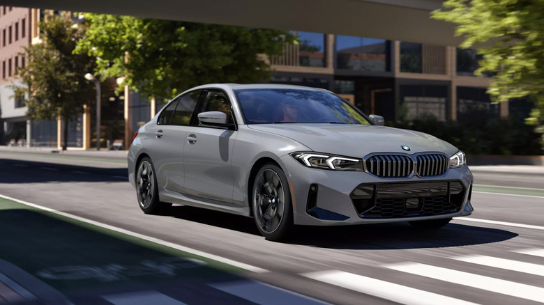 A gray BMW 3 Series driving down a city street.