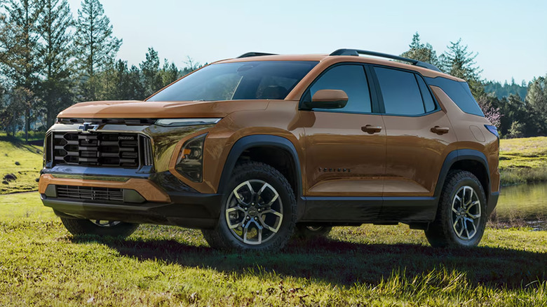 A brown Chevy Equinox on a green grass field near a pond.