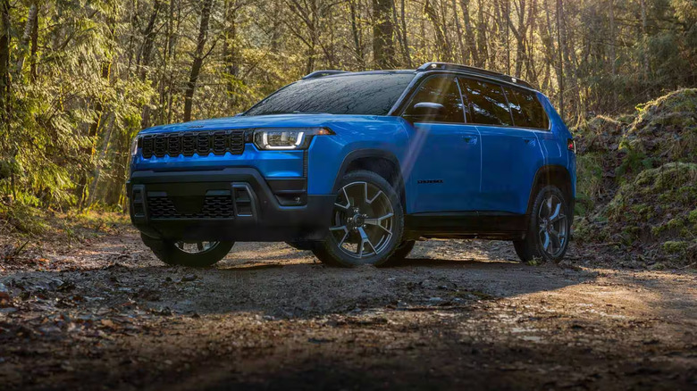 A blue Jeep Cherokee on a forest trail.