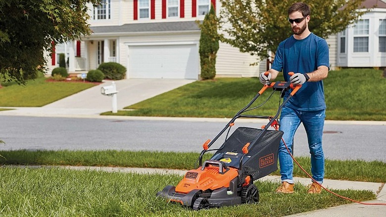 Man using a lawn mower on a small yard.