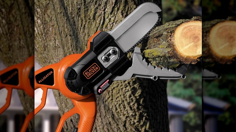 Using an alligator lopper to cut a thick tree branch.
