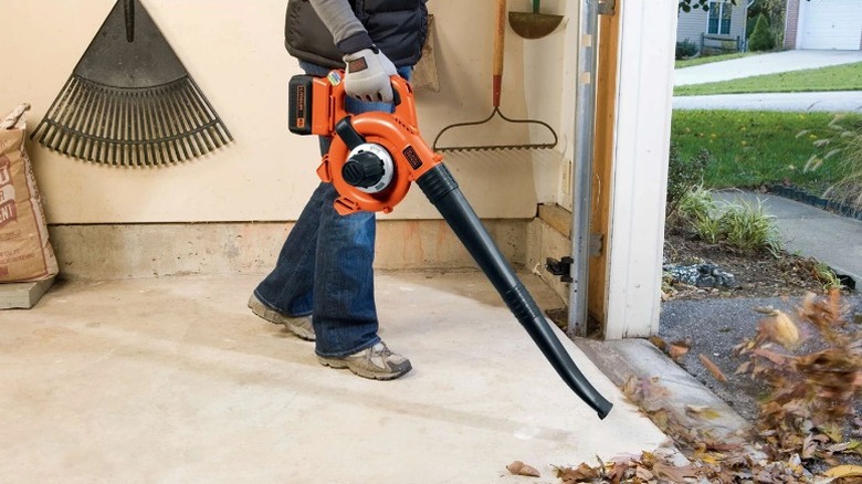 Using a leaf blower to clear out leaves from workshop.