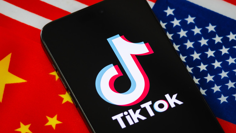 A phone running TikTok with the American and Chinese flags in the background